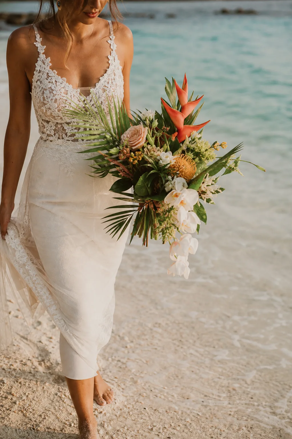 Bride carrying a refined tropical bouquet on a Gili Islands shoreline